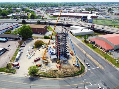 Aerial drone shot of tall steel building under construction with a crane.