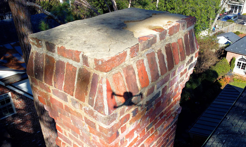 Aerial drone view of English brick chimney top with shadow of drone on chimney.